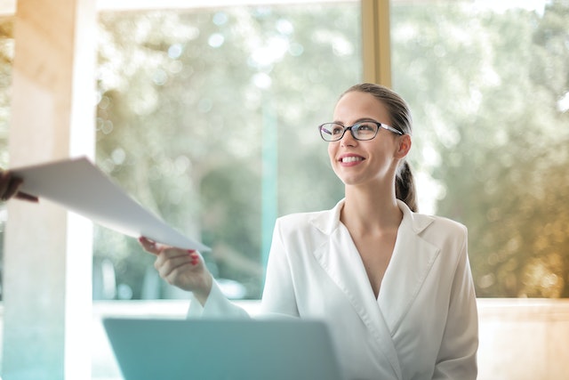 person smiling handing a document to someone off frame